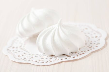 White meringues resting on white decorative mat on light backgroundの写真素材