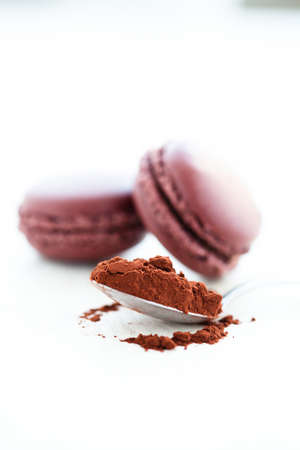 Closeup of cocoa powder in spoon with two macaroons in backgroundの写真素材