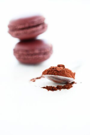Closeup of cocoa powder in spoon with two macaroons in backgroundの写真素材