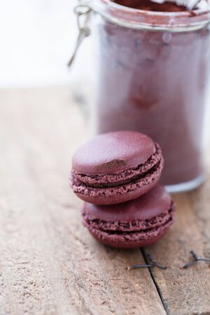 Closeup of two macaroons on wooden table with glass jar of cocoa powder in backgroundの写真素材