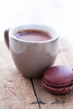 Closeup of cup of hot chocolate and macaroon on a wooden tableの写真素材