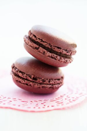 Closeup of two chocolate macaroons on decorative pink matの写真素材