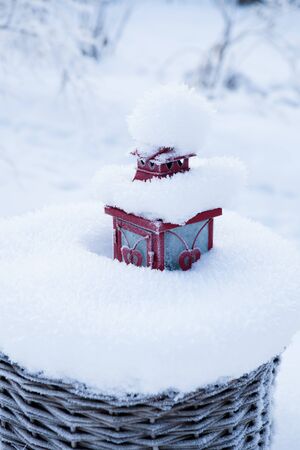 Red lantern resting in snow filled wicker basket outdoors on winter dayの写真素材