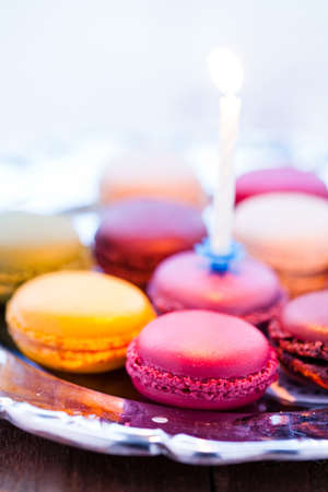 Closeup of macaroons with candle on decorative silver trayの写真素材