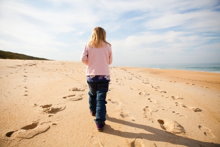 Young girl walking barefoot on beach while on holiday in Portugalの写真素材