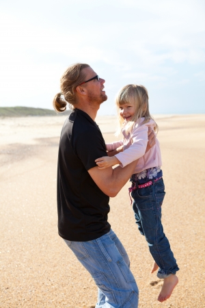 Father holding young daughter in arms at beach while on vacation in Portugalの写真素材