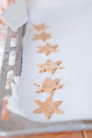 Closeup of row of star shaped gingerbread dough pieces on baking paperの写真素材