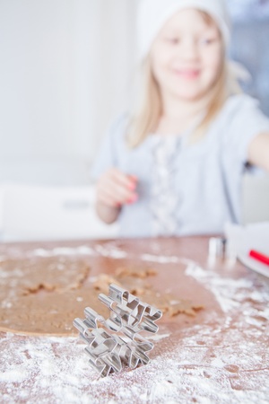 Closeup of star shaped gingerbread dough cutter with happy smiling young girl in backgroundの写真素材