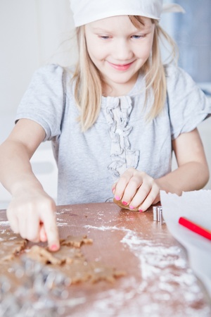 Happy smiling young girl pointing to star shaped piece of dough for making gingerbread biscuitsの写真素材