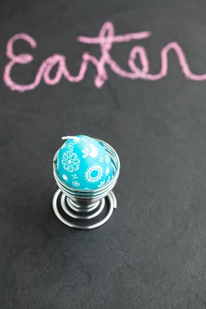 Closeup of blue Easter egg shaped candle with text written in pink chalkの写真素材