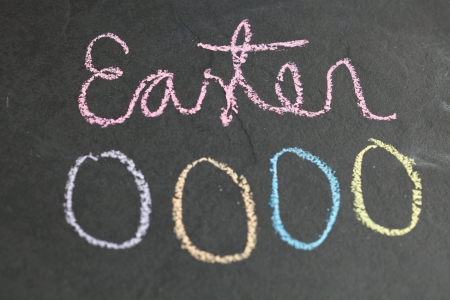 Closeup of four Easter egg shaped chalk drawings and text on dark backgroundの写真素材