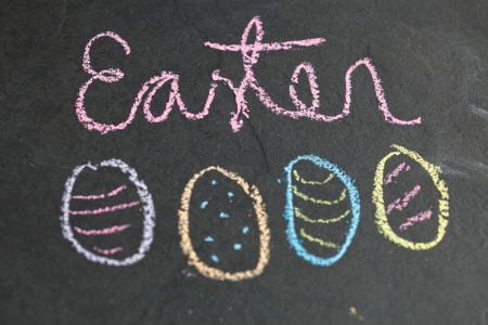 Closeup of four Easter egg shaped chalk drawings and text on dark backgroundの写真素材