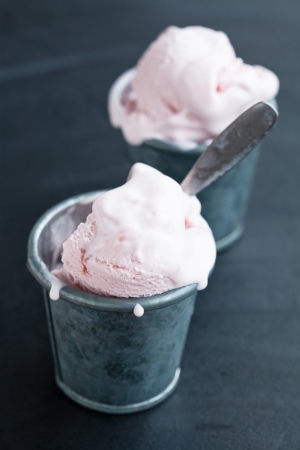 Closeup of strawberry ice cream in two metal cups on dark backgroundの写真素材