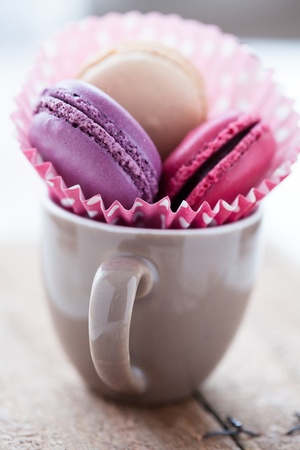 Closeup of three different flavoured macaroons in cup on wooden tableの写真素材