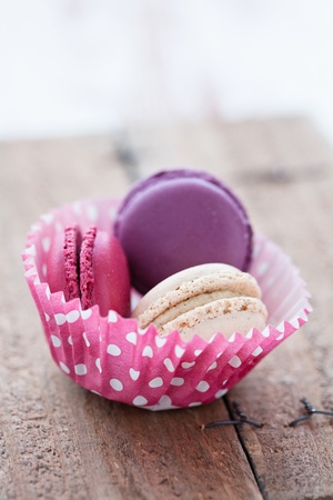 Closeup of three different flavoured macaroons in paper cupcake cup on wooden tableの写真素材