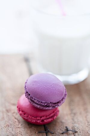 Closeup of two macaroons and glass milk on wooden tableの写真素材