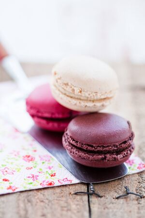 Closeup of three different flavoured macaroons on cake server on wooden tableの写真素材