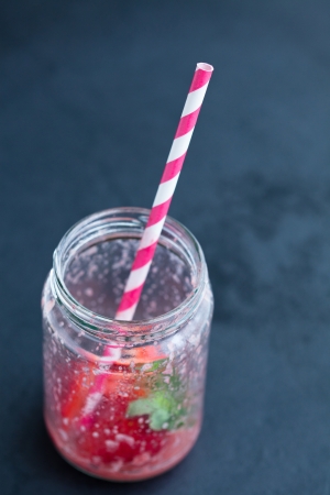 Empty strawberry smoothie glass with striped straw on dark backgroundの写真素材