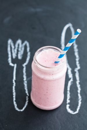 Strawberry smoothie with striped straw with knife and fork chalk drawingの写真素材