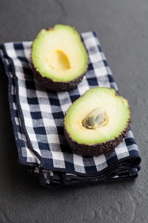 Closeup of fresh avocado halves resting on checkered napkin on dark backgroundの写真素材