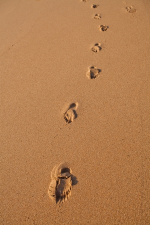 Trail of footprints in smooth sand on beachの写真素材