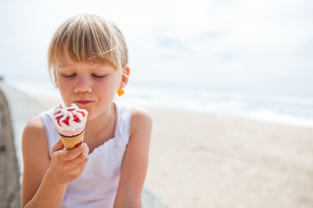 Young cute girl holding ice cream near beachの写真素材