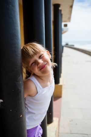 Smiling young girl between structural pillars alongside beachside walkwayの写真素材