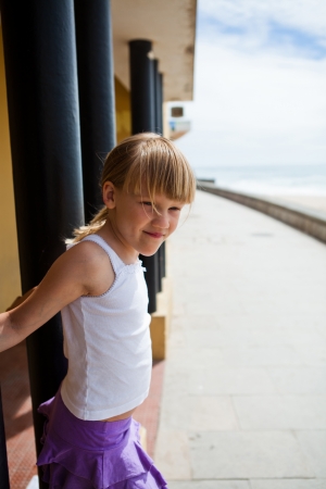 Smiling young girl on beachside walkway with beach and ocean in backgroundの写真素材