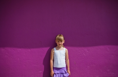 Portrait of cute young girl against purple painted concrete wallの写真素材