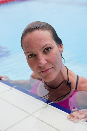 Female swimmer resting at edge of outdoor swimming poolの写真素材