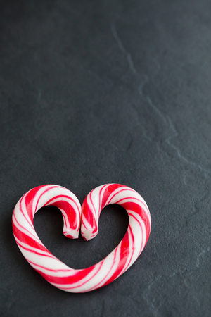 Closeup of hard candy heart with red swirls resting on dark surfaceの写真素材
