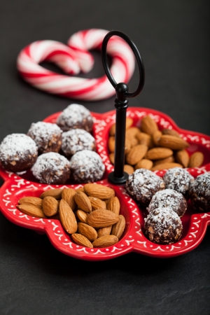 Closeup of tray of almonds and chocolate balls with hard handy heart with red swirls in backgroundの写真素材