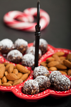 Closeup of tray of almonds and chocolate balls with hard handy heart with red swirls in backgroundの写真素材