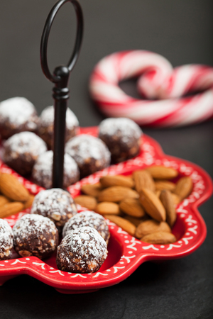 Closeup of tray of almonds and chocolate balls with hard handy heart with red swirls in backgroundの写真素材