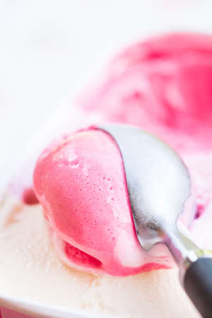 Closeup of raspberry ice cream and metal ice cream scoopの写真素材