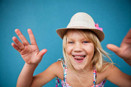 Portrait of stylish cute young girl being playful outside against blue wall backgroundの写真素材