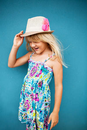 Portrait of stylish cute and happy young girl outside against blue wall backgroundの写真素材