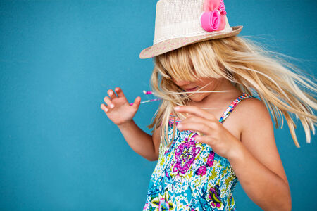 Portrait of stylish cute young girl being playful outside against blue wall backgroundの写真素材