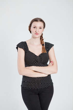 Studio portrait of thoughtful looking attractive woman with pigtail and arms foldedの写真素材