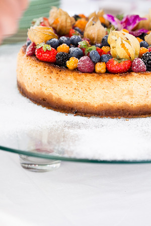 Closeup of delicious sponge cake topped with fresh berries on glass serving trayの写真素材