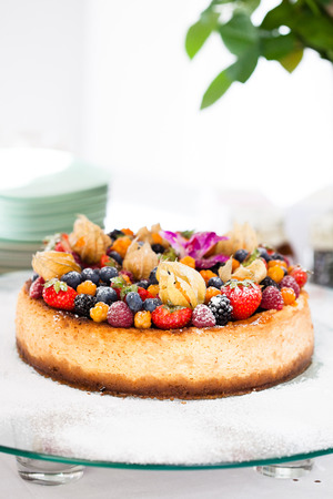 Closeup of delicious sponge cake topped with fresh berries on glass serving trayの写真素材