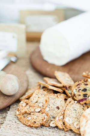 Closeup of dry crackers with cheese on wooden cutting board in backgroundの写真素材