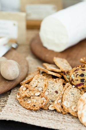 Closeup of dry crackers with cheese on wooden cutting board in backgroundの写真素材