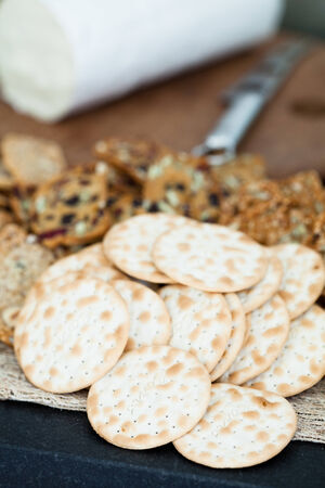 Closeup of dry wafer crackers with cheese on wooden cutting board in backgroundの写真素材