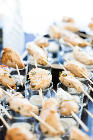 Closeup of pieces of cooked chicken on skewers with mayonnaise based condiment in glassesの写真素材
