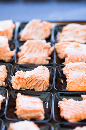 Closeup of salmon appetizers on small serving trays in rowsの写真素材