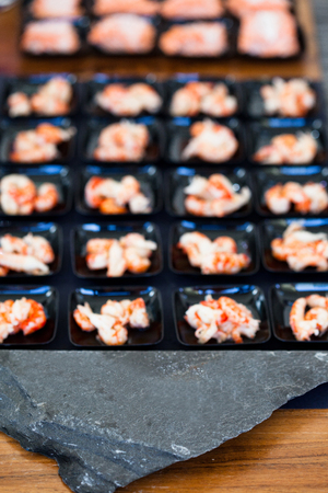 Closeup of shrimp appetizers on small serving trays in rows behind decorative stoneの写真素材