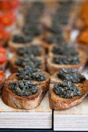 Closeup of bruschetta appetizers with savoury paste topping presented in rowsの写真素材