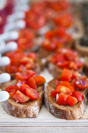 Closeup of bruschetta appetizers with tomato topping presented in rowsの写真素材
