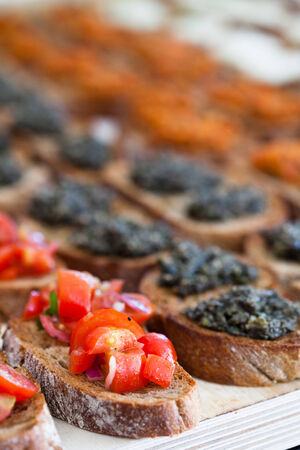 Closeup of bruschetta appetizers with savoury paste and tomato toppings presented in rowsの写真素材